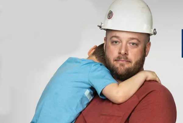 Man in hard hat holding child